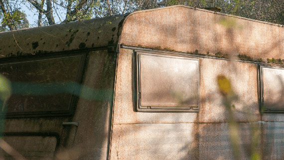 Does Camper Insurance Cover Roof Leaks? A weathered and abandoned camper van sitting in the country side.
